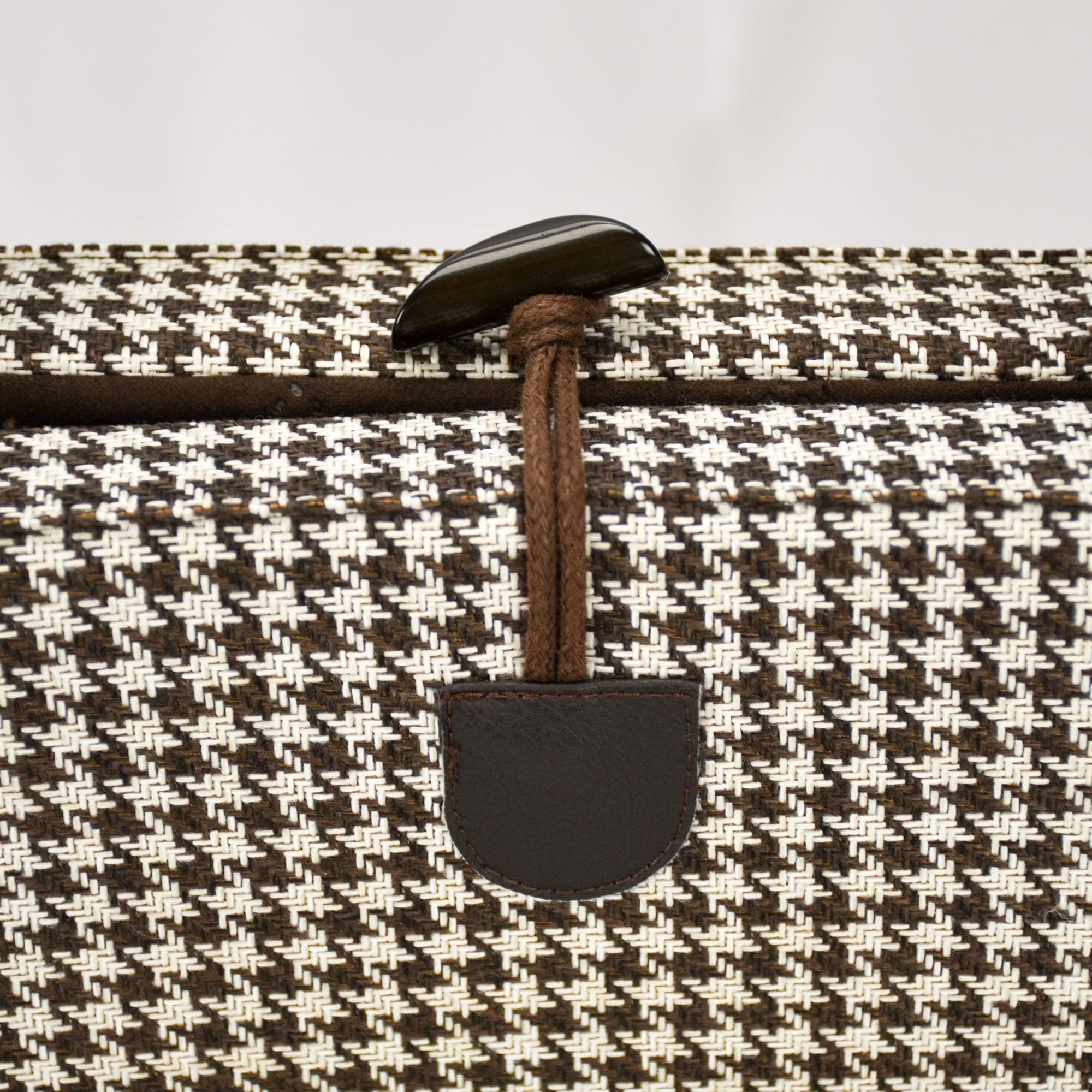 Close up of the convenient one-handed toggle closure in brown on the KONA CAVE® Travel  Dog Bed in brown and white houndstooth for restaurants and pubs. 