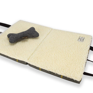 KONA CAVE® luxury portable dog mat for restaurants - unfolded, open Travel Dog Bed with 100% natural sheep's shearling wool lining. Shown with plush dog toy.
