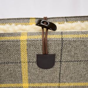 Detail of the plaid portable dog bed with a toggle closure by  KONA CAVE®.
