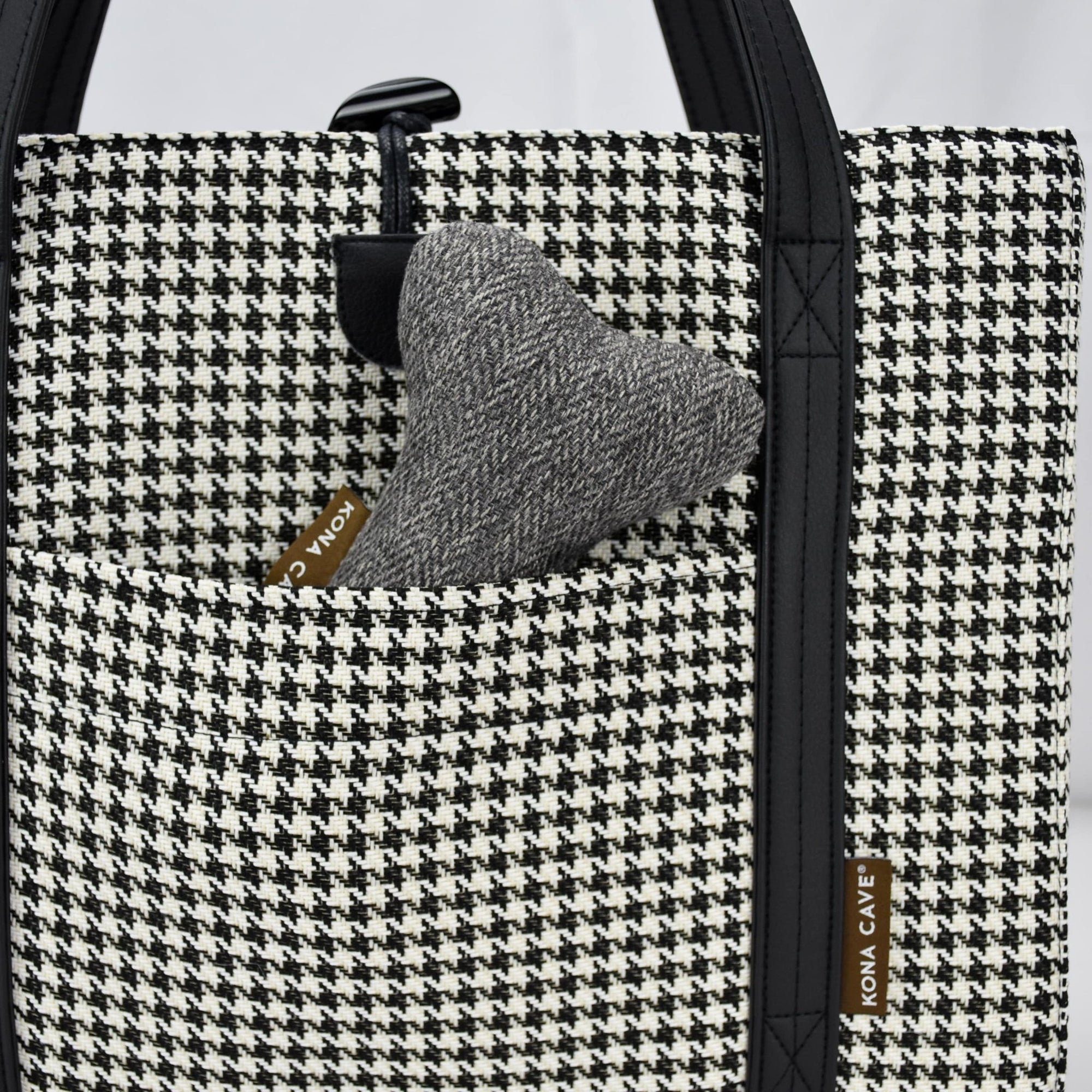 KONA CAVE® luxury Travel Dog Bed in black and white Houndstooth with Black shoulder straps and faux suede lining. Close-up of front pocket shown with toy dog bone. 