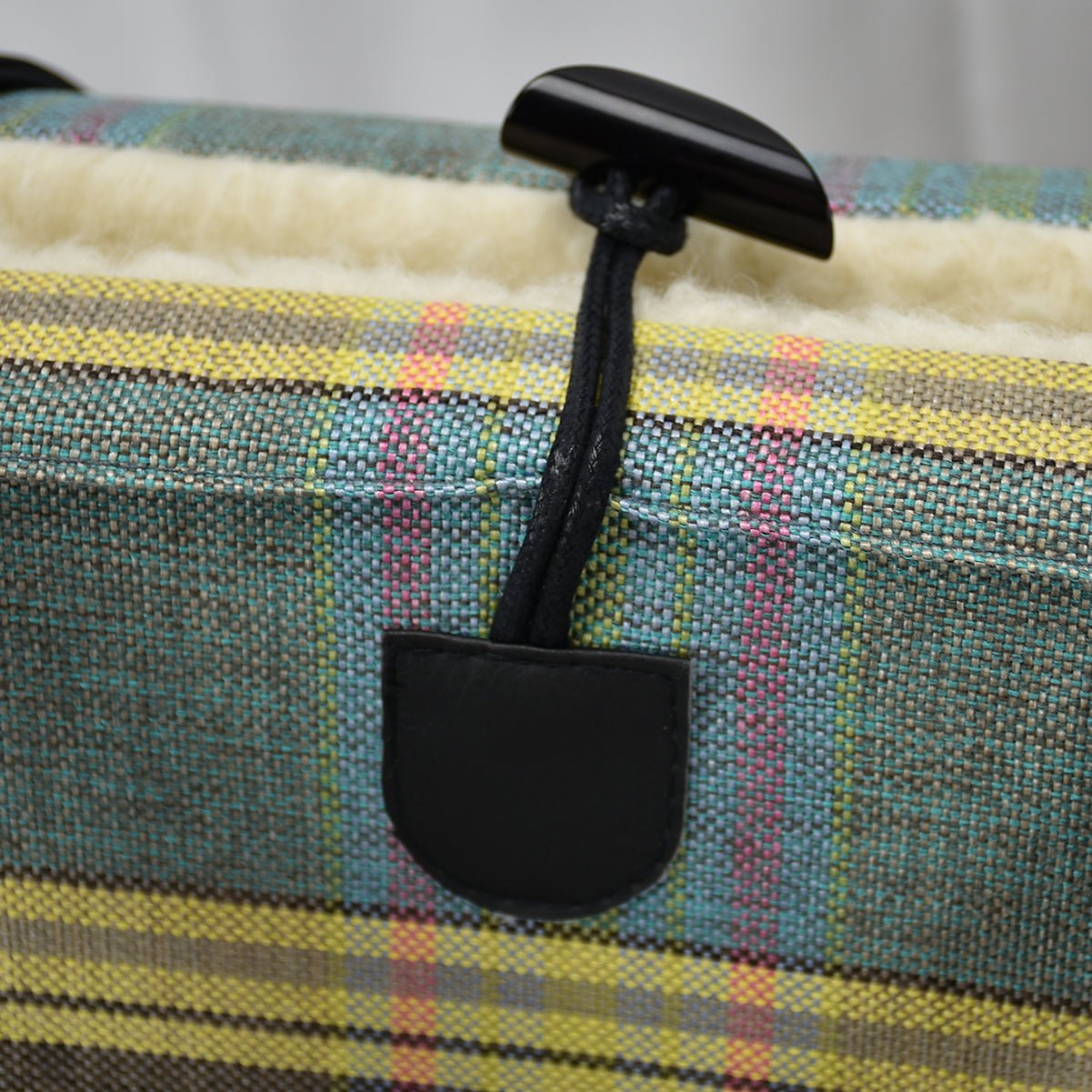 Close-up of KONA CAVE® luxury portable dog bed in pastel plaid fabric. One-handed toggle closure in black for easy opening and closing of the KONA CAVE® Travel Dog Bed